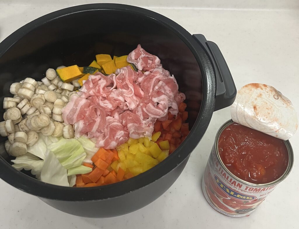 ホットクックの内釜に入れたスープの具材と開封したトマト缶の並び写真⁠

